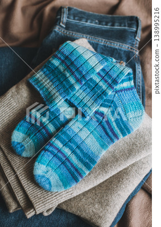 Hand knitted blue socks with sweater and jeans. Concept for handmade and hygge slow life. Hand knitted blue socks with sweater and jeans. Concept for handmade and hygge slow life. 138995216