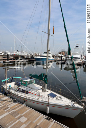 A scene of yachts moored at the marina's pier against a blue sky. A scene of yachts moored at the marina's pier against a blue sky. 138995315