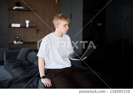 Casual browsing in cozy room. Man unwinding on sofa with laptop Casual browsing in cozy room. Man unwinding on sofa with laptop 138995338