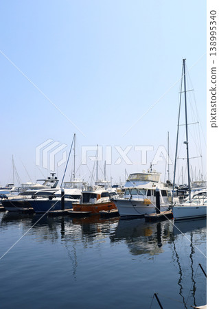 A scene of luxurious yachts and cruisers moored in a marina on a calm, sunny day. A scene of luxurious yachts and cruisers moored in a marina on a calm, sunny day. 138995340