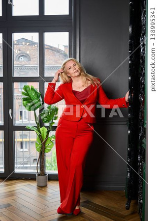 Fashionable woman leaning against window with city view Fashionable woman leaning against window with city view 138995341