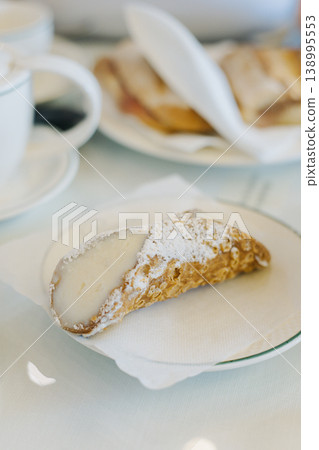 Sweet cannoli stuffed with cream for breakfast on a table in a cafe. 138995553