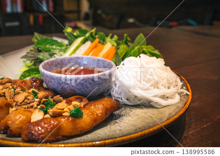 Vietnamese roast pork dish, Nem Nuong. Close-up of herbs, vegetables, and sauce. 138995586