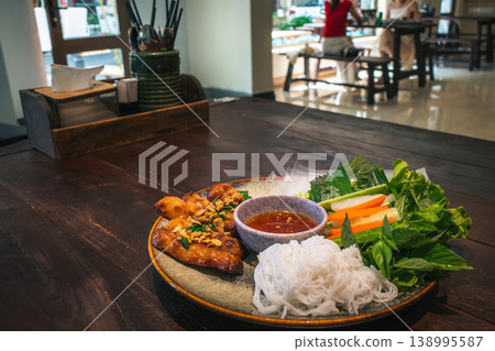 Vietnamese dishes, Nem Nuong, lined up inside the restaurant. Wooden tables and presentation Vietnamese dishes, Nem Nuong, lined up inside the restaurant. Wooden tables and presentation 138995587