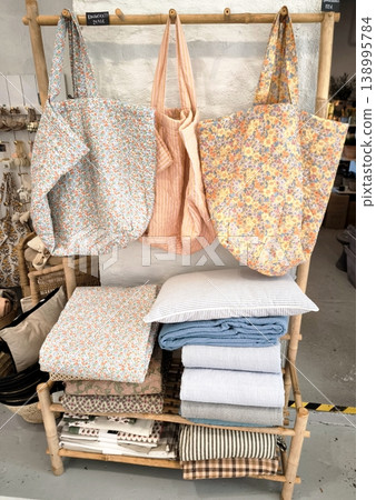 Eco-friendly bags with floral prints and stacks of textiles made from natural fabrics in Scandinavian style. Eco-friendly bags with floral prints and stacks of textiles made from natural fabrics in Scandinavian style. 138995784
