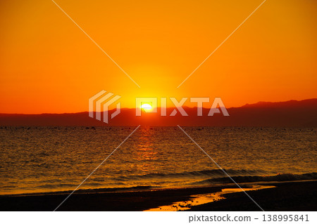 The sky and sea are dyed orange by the morning sun. The sky and sea are dyed orange by the morning sun. 138995841