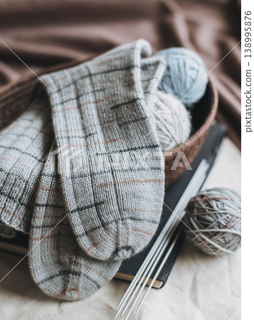 Hand knitted socks with needles and yarn ball in a basket. Concept for handmade and hygge slow life. Hand knitted socks with needles and yarn ball in a basket. Concept for handmade and hygge slow life. 138995876
