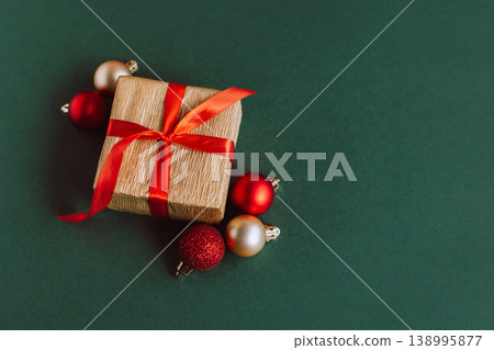 Gift box with red and golden balls on a green background. Holiday concept. 138995877