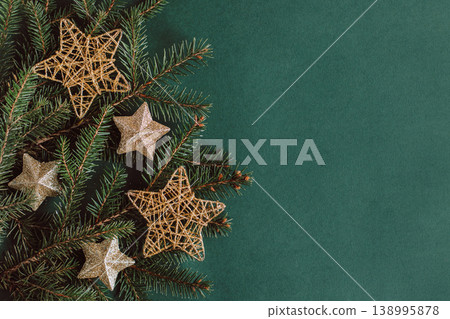 Spruce branches with golden sparkling stars on a dark green background. Spruce branches with golden sparkling stars on a dark green background. 138995878