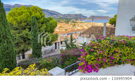 Charming Altea city panorama revealing terracotta rooftops, cypress trees, and vibrant bougainvillea against the calm Mediterranean Sea and distant Spanish mountains, ideal for family holidays 138995904