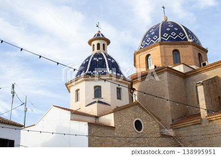 Altea Spain's charming blue and white tiled church domes rise against a bright daytime sky, a prominent landmark for travelers exploring this beautiful Mediterranean city on family holidays 138995951