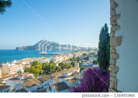 Coastal panorama of Altea city in Spain showcasing the Mediterranean Sea, a busy marina, whitewashed buildings, and scenic mountains under a clear blue sky, perfect for holidays and family vacation 138995960