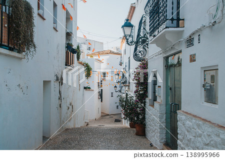 Exploring a charming narrow cobbled street in Altea Old Town Spain, adorned with whitewashed buildings and traditional lanterns, perfect for a memorable family holiday vacation Exploring a charming narrow cobbled street in Altea Old Town Spain, adorned with whitewashed buildings and traditional lanterns, perfect for a memorable family holiday vacation 138995966