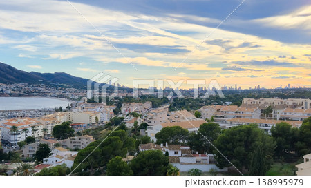 Evening panoramic cityscape of Altea, Spain, highlighting the vibrant bay, coastal architecture, and majestic mountains, perfect for family holidays and tourism Evening panoramic cityscape of Altea, Spain, highlighting the vibrant bay, coastal architecture, and majestic mountains, perfect for family holidays and tourism 138995979