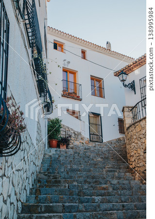 Picturesque cobblestone steps ascending between traditional whitewashed houses and flowering balconies in the historic heart of Altea, Spain, inviting travelers to explore the charming streets 138995984
