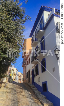 Altea Spain charming narrow street with traditional white and blue buildings under a clear blue sky, perfect for family holidays and tourism exploration 138995988