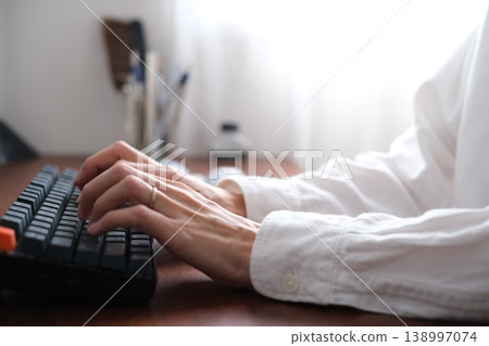 Hands of a man typing on a keyboard while working remotely Hands of a man typing on a keyboard while working remotely 138997074