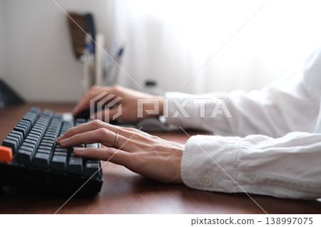 Hands of a man typing on a keyboard while working remotely Hands of a man typing on a keyboard while working remotely 138997075