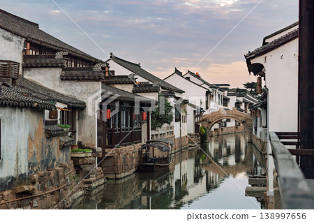Historic Chinese water town architecture frames a tranquil canal with a classic stone bridge under a soft morning sky Historic Chinese water town architecture frames a tranquil canal with a classic stone bridge under a soft morning sky 138997656