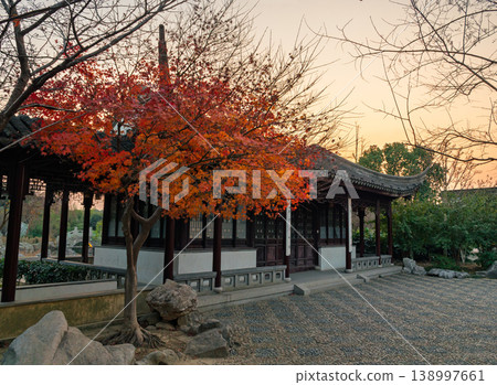 A traditional Chinese pavilion with a curved roof stands amidst vibrant red and orange maple trees in a peaceful classical garden. A traditional Chinese pavilion with a curved roof stands amidst vibrant red and orange maple trees in a peaceful classical garden. 138997661