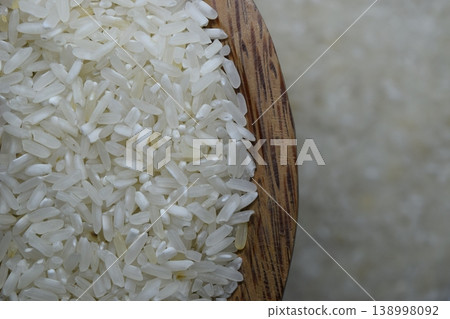 Raw rice in wooden bowl on a blur background. Raw rice in wooden bowl on a blur background. 138998092