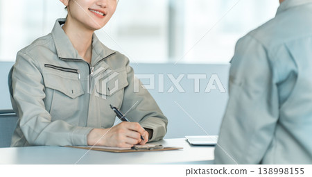 Male and female manufacturing and factory workers in work clothes holding a meeting/discussion in a conference room. Male and female manufacturing and factory workers in work clothes holding a meeting/discussion in a conference room. 138998155
