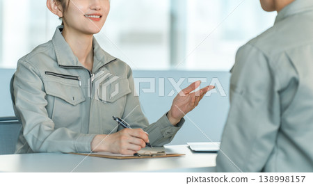Male and female manufacturing and factory workers in work clothes holding a meeting/discussion in a conference room. Male and female manufacturing and factory workers in work clothes holding a meeting/discussion in a conference room. 138998157