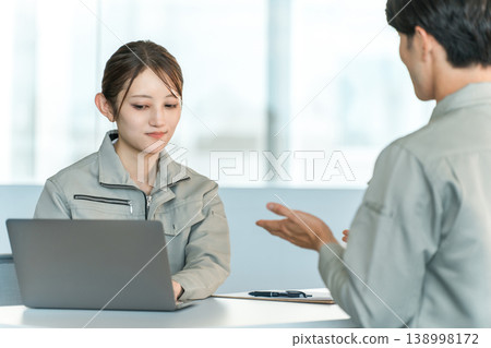 身著工作服的男女製造工人和工廠工人在會議室開會/討論。 138998172