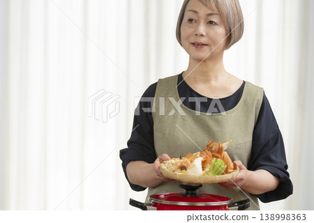 廚房裡,一位老婦人正在煮蔬菜湯。 廚房裡,一位老婦人正在煮蔬菜湯。 138998363