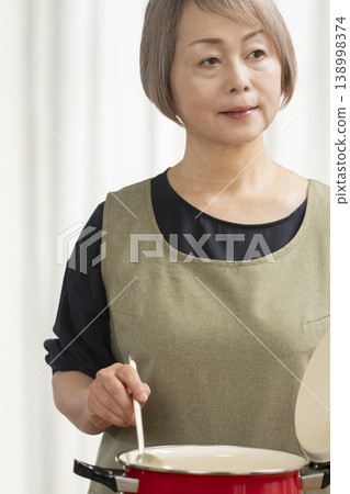 廚房裡,一位老婦人正在煮蔬菜湯。 廚房裡,一位老婦人正在煮蔬菜湯。 138998374