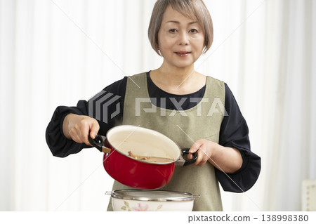 Senior woman making vegetable broth in the kitchen Senior woman making vegetable broth in the kitchen 138998380