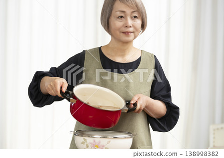 廚房裡,一位老婦人正在煮蔬菜湯。 廚房裡,一位老婦人正在煮蔬菜湯。 138998382