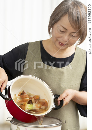 廚房裡,一位老婦人正在煮蔬菜湯。 廚房裡,一位老婦人正在煮蔬菜湯。 138998390
