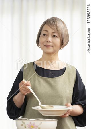 廚房裡,一位老婦人正在煮蔬菜湯。 廚房裡,一位老婦人正在煮蔬菜湯。 138998398