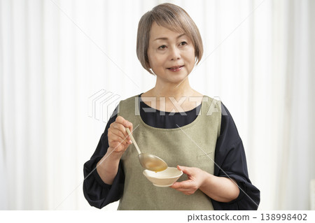 廚房裡,一位老婦人正在煮蔬菜湯。 廚房裡,一位老婦人正在煮蔬菜湯。 138998402