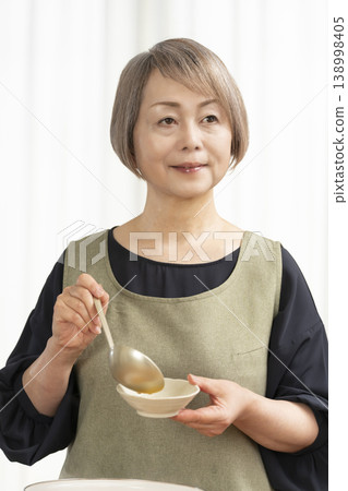 廚房裡,一位老婦人正在煮蔬菜湯。 廚房裡,一位老婦人正在煮蔬菜湯。 138998405