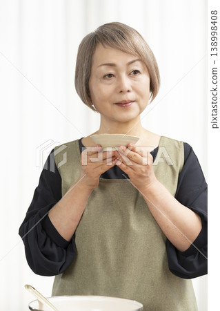 廚房裡,一位老婦人正在煮蔬菜湯。 廚房裡,一位老婦人正在煮蔬菜湯。 138998408