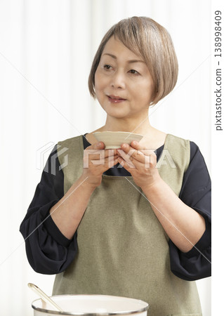 廚房裡,一位老婦人正在煮蔬菜湯。 廚房裡,一位老婦人正在煮蔬菜湯。 138998409