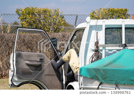 A worker stretches out his legs and takes a nap in the driver's seat of a light truck. A worker stretches out his legs and takes a nap in the driver's seat of a light truck. 138998761