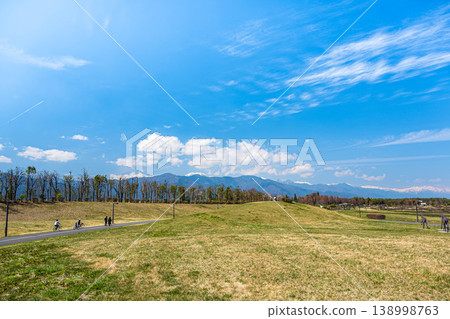 People enjoying cycling at Shinshu Sky Park in spring, with views of the snow-capped Northern Alps. People enjoying cycling at Shinshu Sky Park in spring, with views of the snow-capped Northern Alps. 138998763
