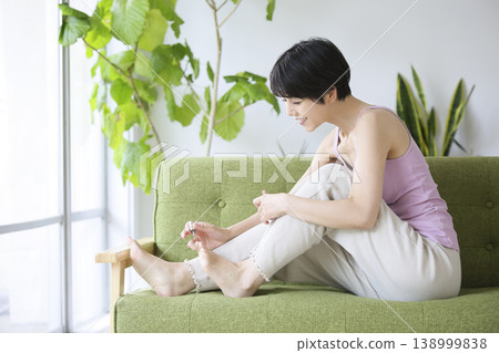 一位女士在客廳放鬆地做足療。 一位女士在客廳放鬆地做足療。 138999838