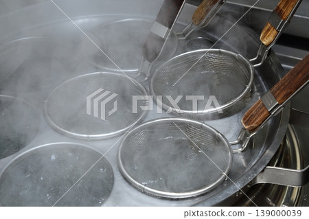 A scene of noodles being boiled in a ramen shop, with steam rising from the kitchen (during cooking). 139000039