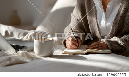 Cozy morning bed notebook coffee laptop handwriting person writing notes notebook bed beside coffee mug and laptop, cozy morning light, home office remote work, warm cardigan, calm routine Cozy morning bed notebook coffee laptop handwriting person writing notes notebook bed beside coffee mug and laptop, cozy morning light, home office remote work, warm cardigan, calm routine 139000555