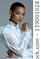 Portrait woman fashion jacket transparent reflective Studio portrait of woman wearing transparent reflective jacket, modern futuristic fashion styling, confident pose, close up beauty look gray 139001028