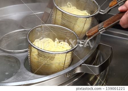 Close-up of Chinese noodles being boiled in a noodle boiling machine, and the steam rising from them. 139001221