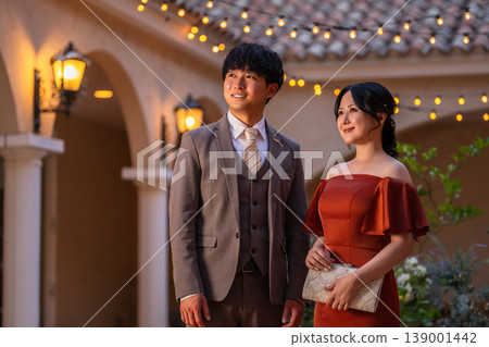 一對盛裝打扮的新人,身穿彩色禮服,在婚禮場地舉行夜間婚禮。 一對盛裝打扮的新人,身穿彩色禮服,在婚禮場地舉行夜間婚禮。 139001442