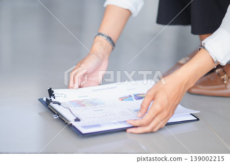 Hands arranging summary reports on a clipboard with charts and graphs in a clean office space. Business documentation, data presentation, paperwork management, and financial planning concept. 139002215