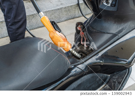Filling scooter fuel tank with gasoline at petrol station close view Filling scooter fuel tank with gasoline at petrol station close view 139002943