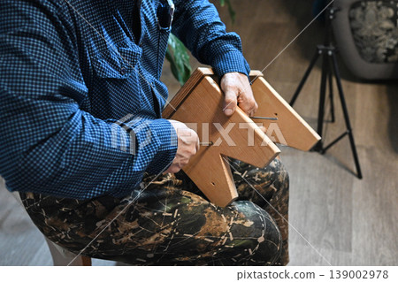 Man using power drill to assemble furniture in home setting during daytime Man using power drill to assemble furniture in home setting during daytime 139002978