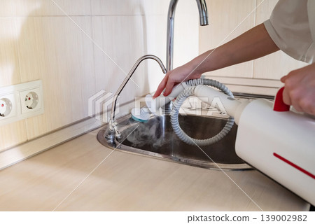Cleaning the kitchen surface with a steam cleaner next to the sink at home 139002982